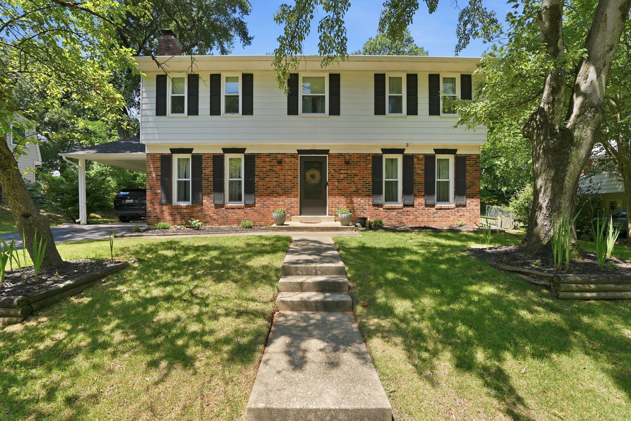 Charming three-story home with lush greenery.