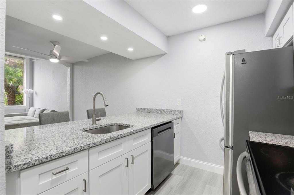 5846 Peregrine Avenue, Unit B12 Orlando, FL 32819 - Photo 5 of 30 a kitchen with stainless steel appliances granite countertop a refrigerator and a sink
