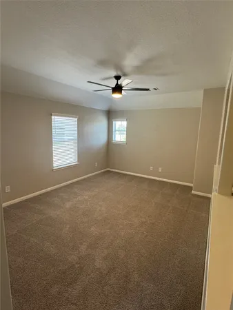 an empty room with windows and ceiling fan