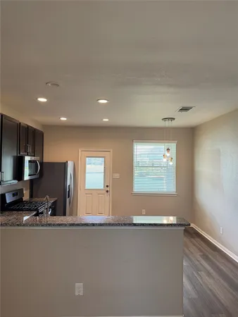 a view of kitchen with stainless steel appliances wooden floor and window