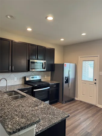 a kitchen with stainless steel appliances granite countertop a refrigerator stove microwave and sink
