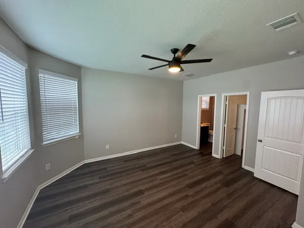 an empty room with wooden floor and windows
