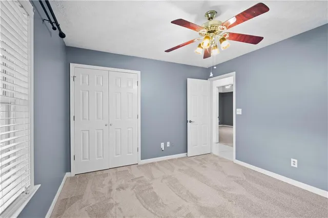 a view of an empty room with window and a kitchen