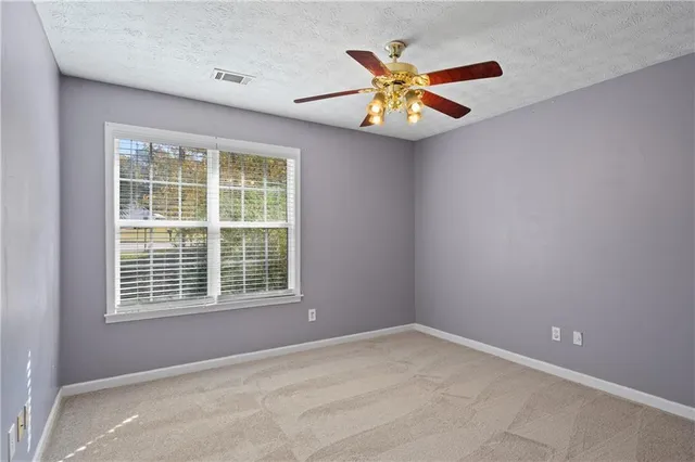 a view of an empty room with a window and a ceiling fan
