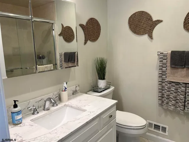 a bathroom with a granite countertop toilet sink and mirror