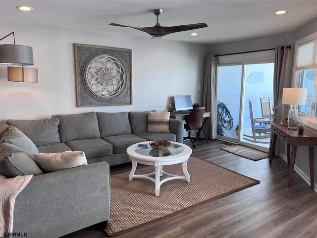a living room with furniture a large window and wooden floor