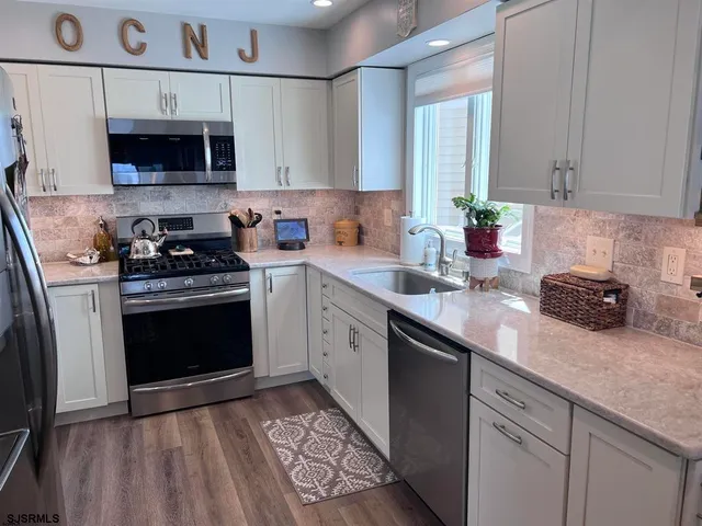 a kitchen with stainless steel appliances granite countertop a sink a stove a microwave and cabinets