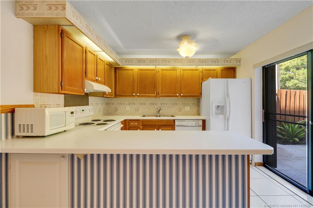 5662 Southeast Windsong Lane, Unit 408 Stuart, FL 34997 - Photo 16 of 35 a kitchen with a refrigerator a stove a sink dishwasher and wooden cabinets with wooden floor