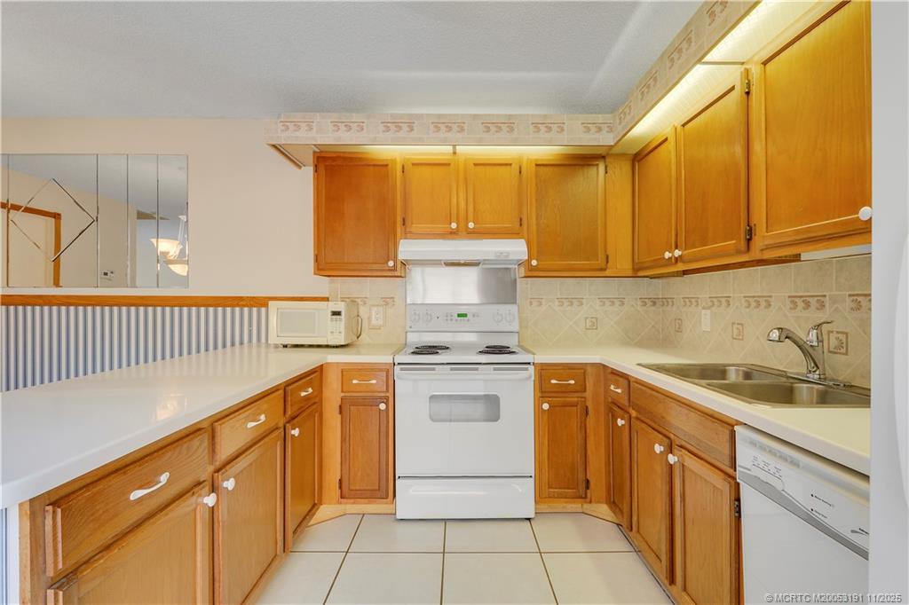 5662 Southeast Windsong Lane, Unit 408 Stuart, FL 34997 - Photo 19 of 35 a kitchen with a sink stove and cabinets
