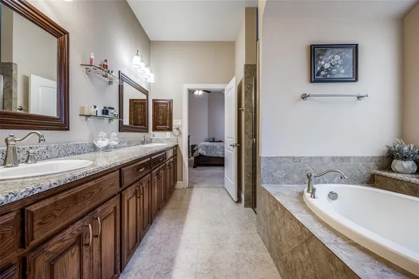 a bathroom with a granite countertop double vanity sink and a bathtub