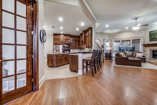 a living room with stainless steel appliances furniture wooden floor and a kitchen view