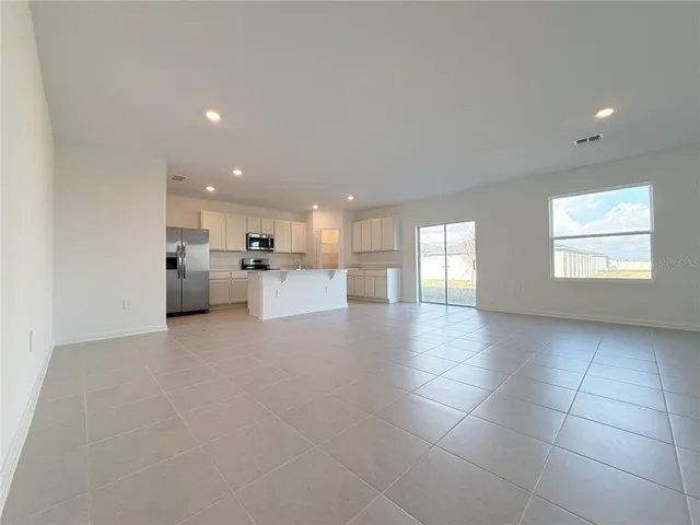 a view of empty room with kitchen and window