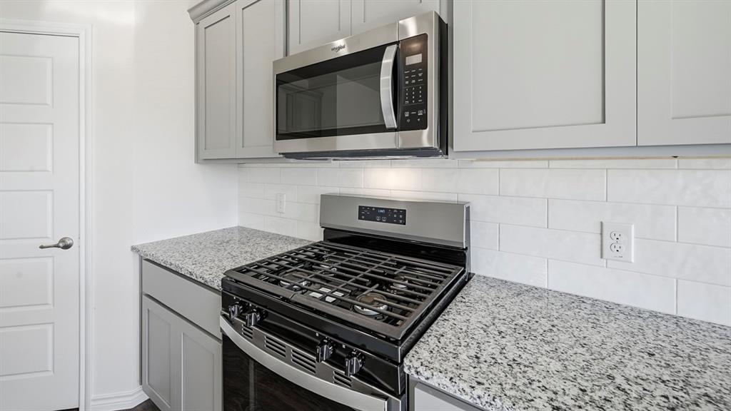 419 Epiphany Lane Lavon, TX 75166 - Photo 8 of 31 Kitchen featuring light grey cabinetry, a stainless steel gas range, an over-the-range microwave, granite countertops, and a white subway tile backsplash