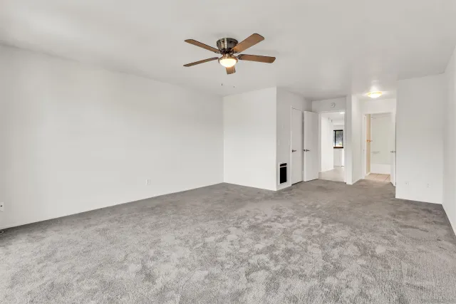 an empty room with closet and ceiling fan