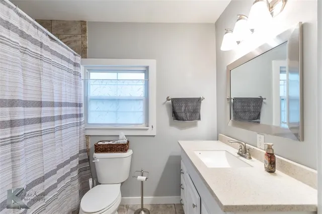 a bathroom with a granite countertop toilet sink and mirror