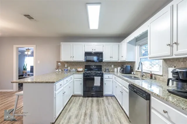 a large kitchen with a white cabinets sink and stainless steel appliances