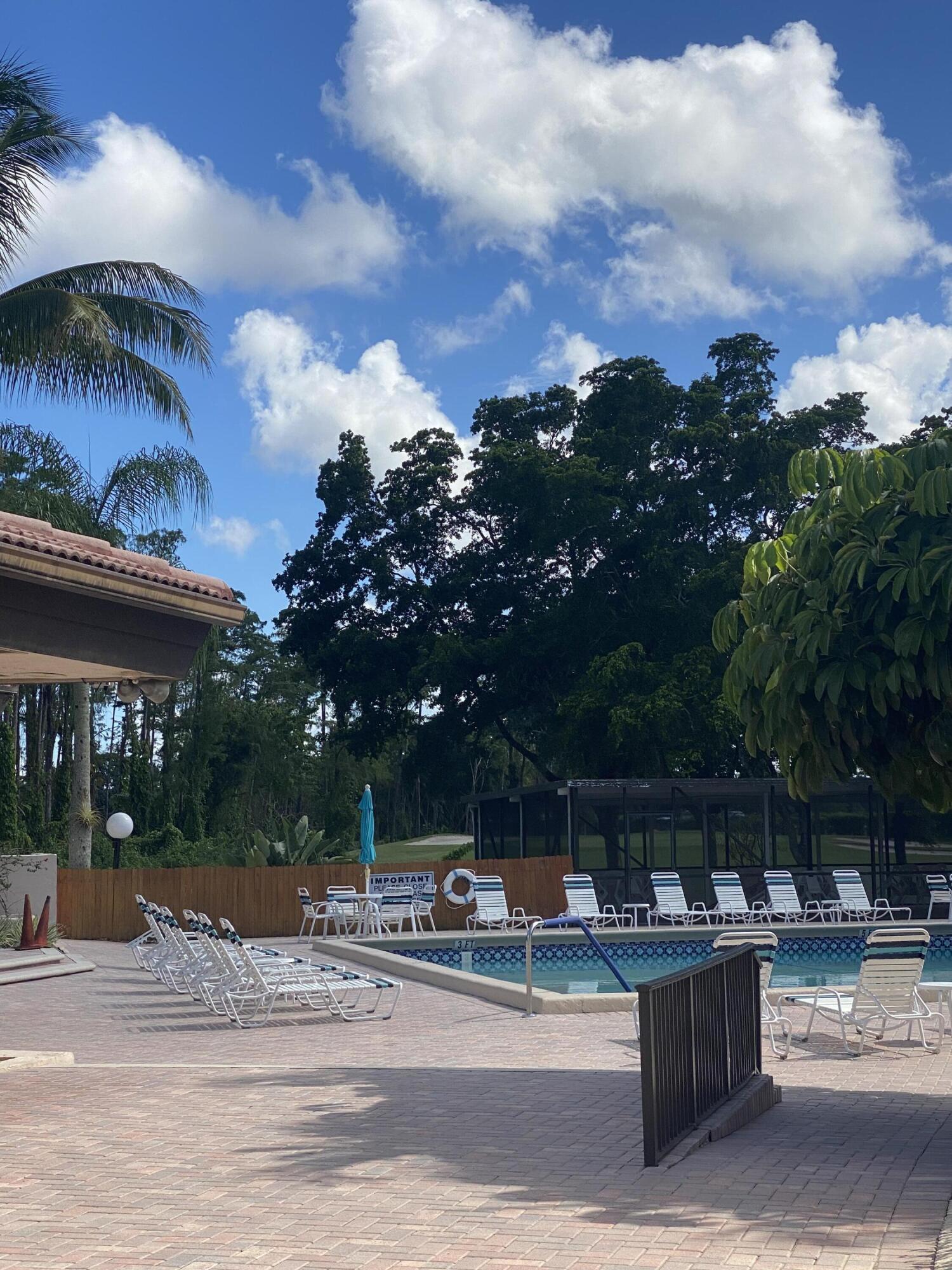 21506 Juego Circle, Unit 28H Boca Raton, FL 33433 - Photo 18 of 21 a view of the patio with dining table and chairs with a fire pit and a fire pit