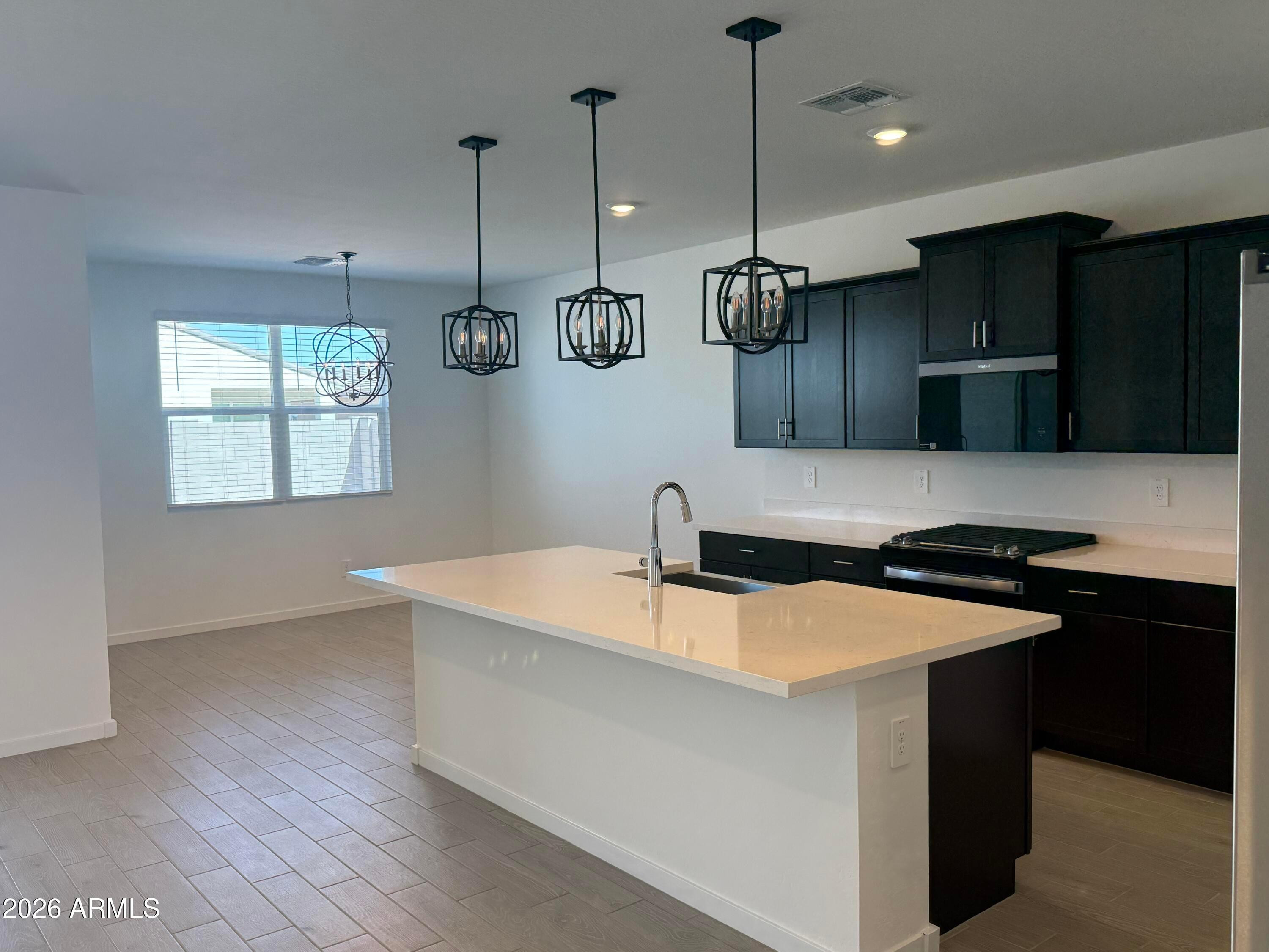 2478 Grenache Road San Tan Valley, AZ 85143 - Photo 3 of 34 a kitchen with stainless steel appliances granite countertop a sink a stove and a wooden floors