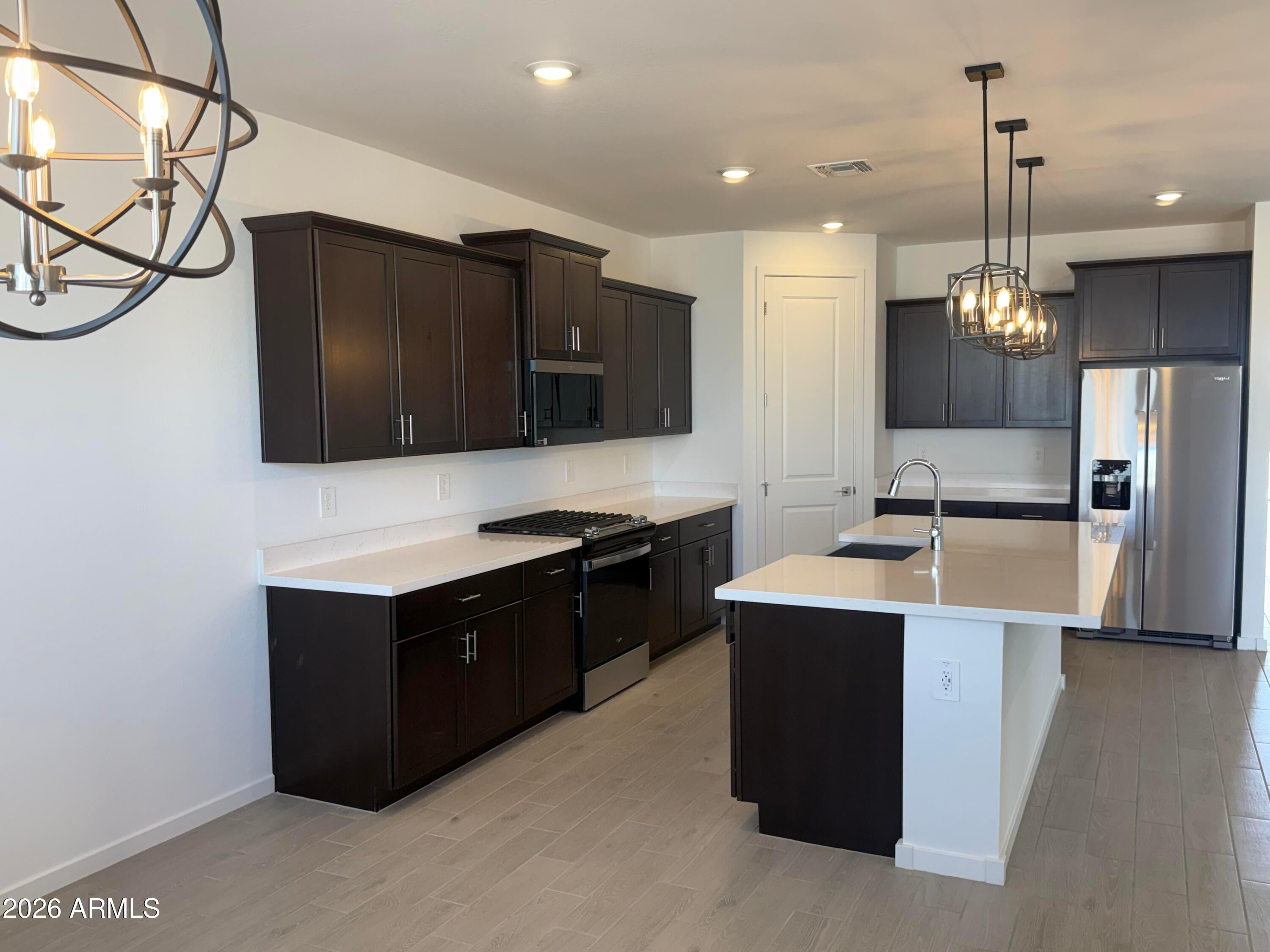 2478 Grenache Road San Tan Valley, AZ 85143 - Photo 4 of 34 a kitchen with stainless steel appliances granite countertop a sink a stove and a refrigerator with wooden floor