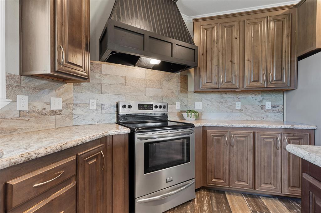 3449 Bluhm Road West, TX 76691 - Photo 11 of 40 Kitchen with stainless steel appliances, premium range hood, tasteful backsplash, dark wood-type flooring, and light stone counters