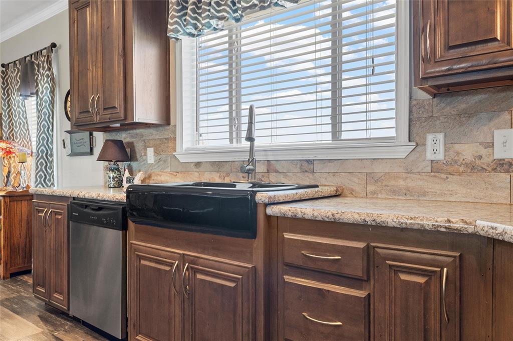 3449 Bluhm Road West, TX 76691 - Photo 14 of 40 Kitchen with dark brown cabinets, decorative backsplash, dishwasher, crown molding, and light stone counters