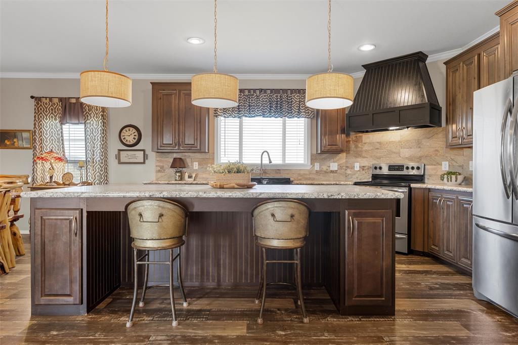 3449 Bluhm Road West, TX 76691 - Photo 15 of 40 Kitchen with decorative backsplash, a center island, custom range hood, ornamental molding, and appliances with stainless steel finishes