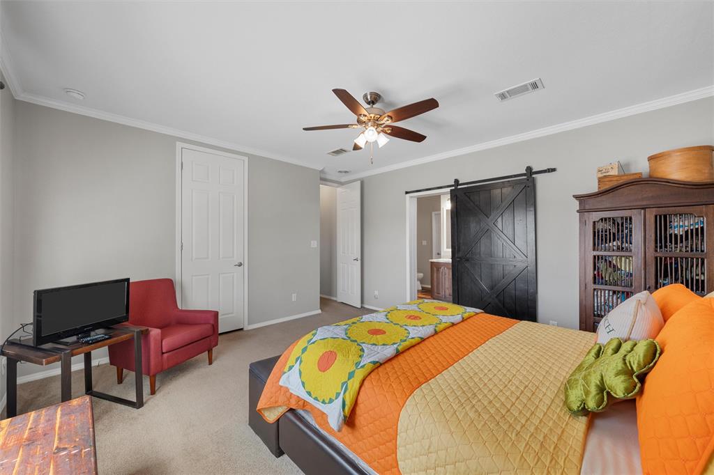 3449 Bluhm Road West, TX 76691 - Photo 16 of 40 Carpeted bedroom featuring a barn door, crown molding, a ceiling fan, a closet, and ensuite bath