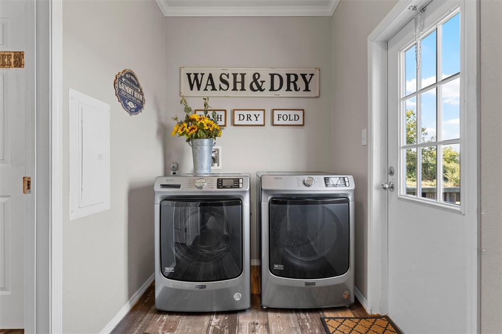 3449 Bluhm Road West, TX 76691 - Photo 29 of 40 Laundry area featuring electric panel, washer and clothes dryer, wood finished floors, and ornamental molding