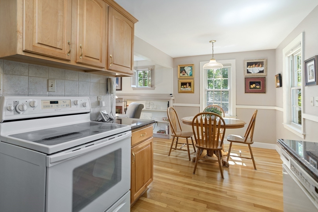 42 Sturges Road Reading, MA 01867 - Photo 15 of 42 a kitchen with stainless steel appliances granite countertop a stove a sink a dining table and chairs with wooden floor