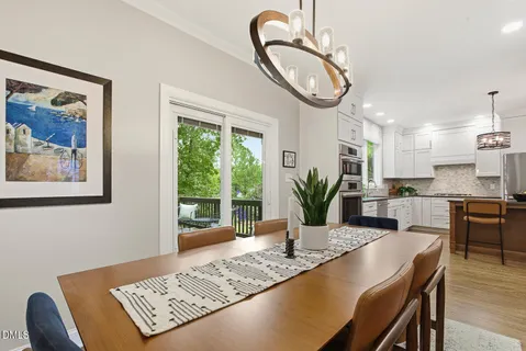 a kitchen with stainless steel appliances kitchen island granite countertop a stove a microwave a dining table and chairs with wooden floor