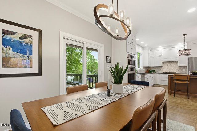 a kitchen with stainless steel appliances kitchen island granite countertop a stove a microwave a dining table and chairs with wooden floor