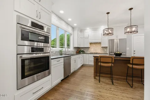 a very nice looking kitchen with granite countertop a stove two sink and stainless steel appliances