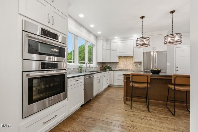 a very nice looking kitchen with granite countertop a stove two sink and stainless steel appliances