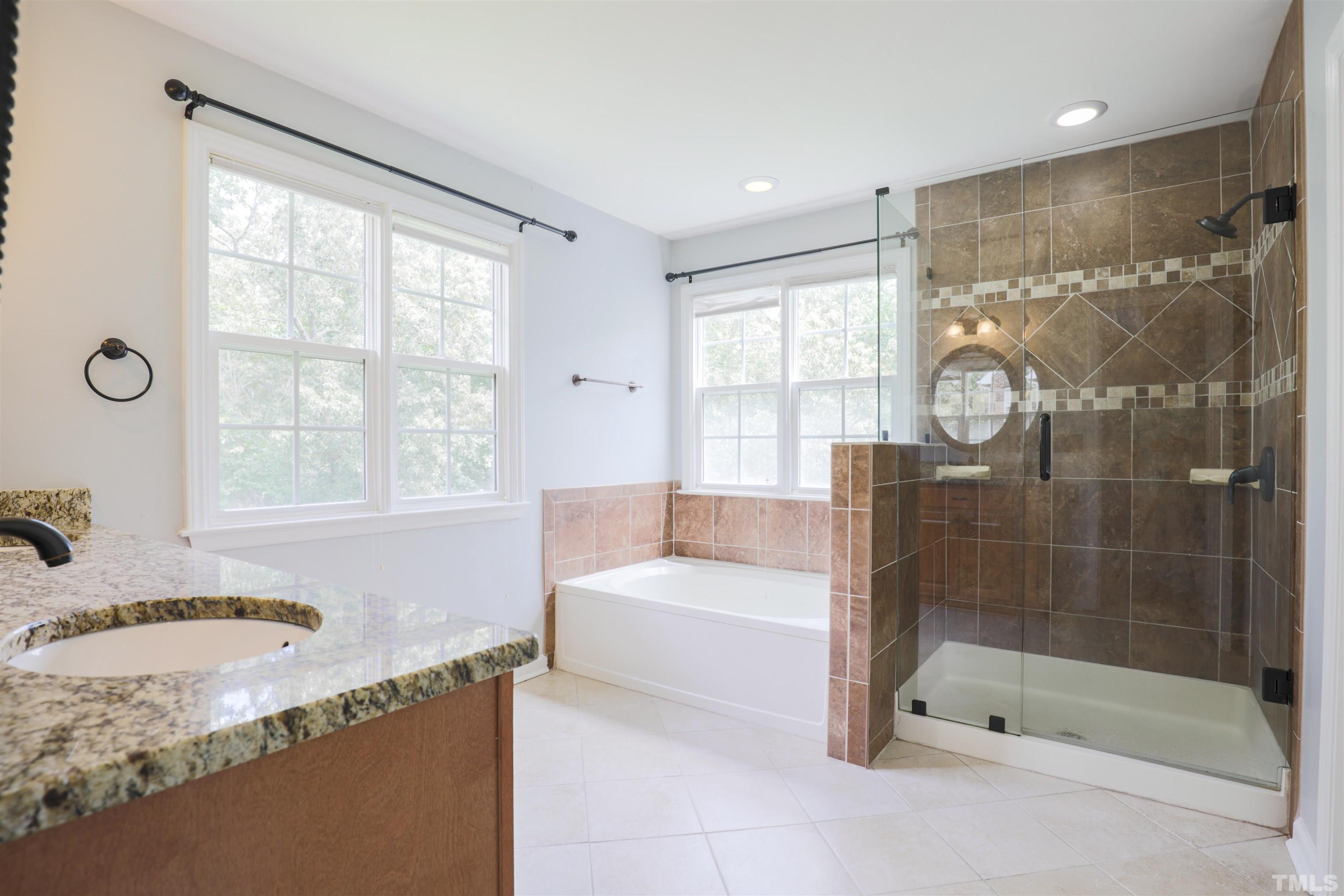4709 Treadstone Court Raleigh, NC 27616 - Photo 6 of 22 a bathroom with a granite countertop tub a sink and a large window