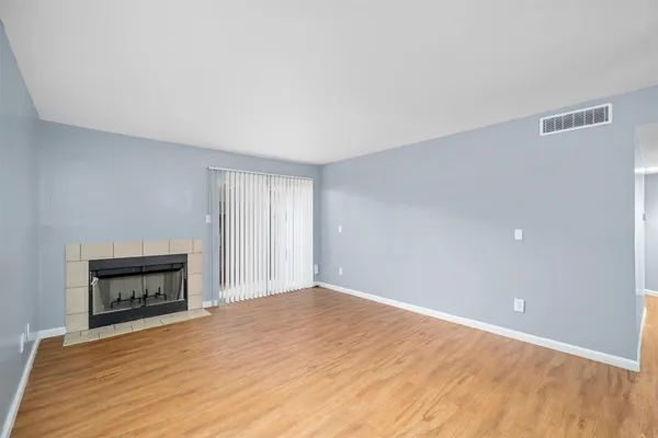 a big room with wooden floor a fireplace and a window
