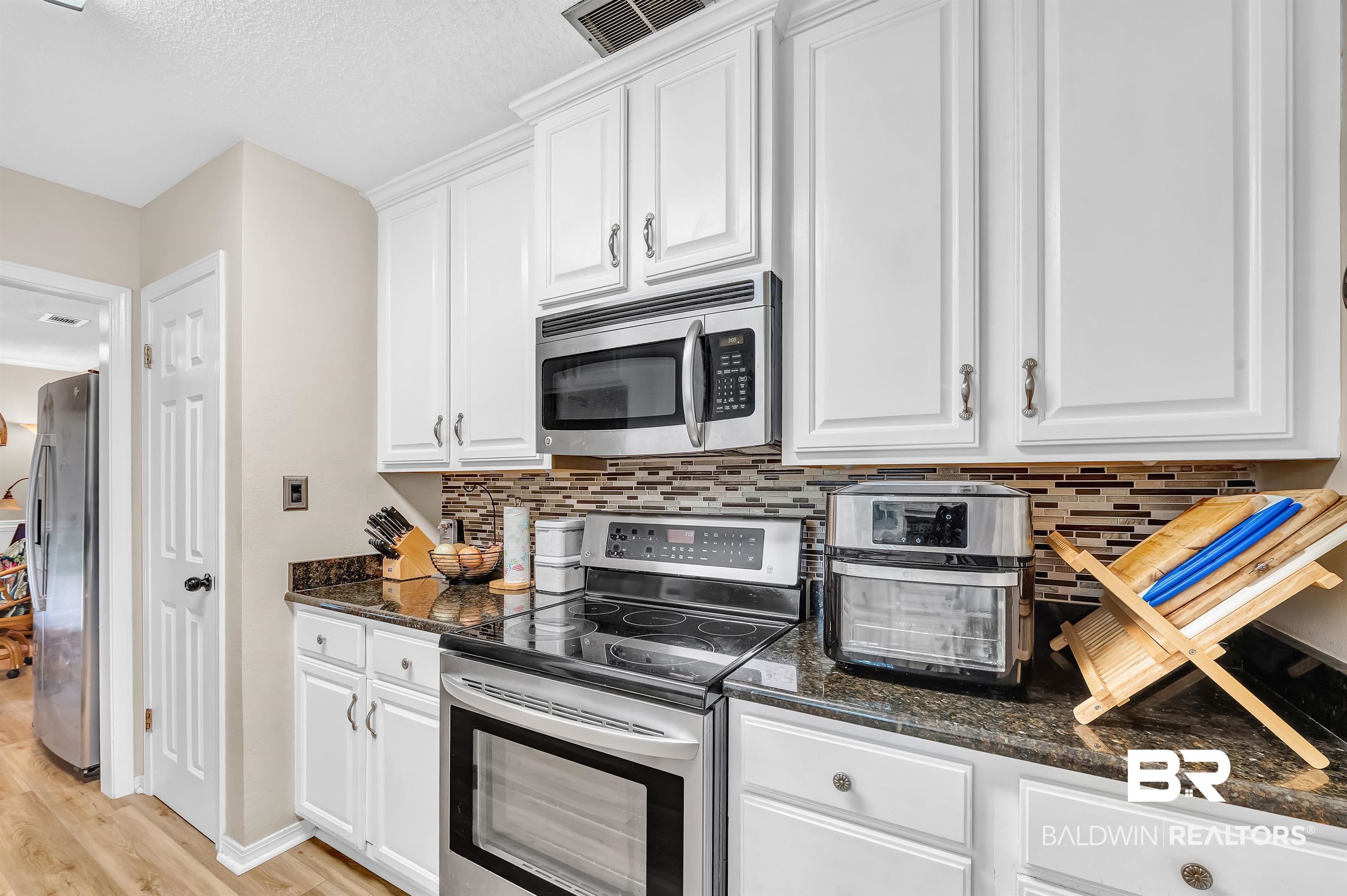 24551 Wolf Bay Drive Foley, AL 36535 - Photo 28 of 59 Kitchen with stainless steel appliances, white cabinets, backsplash, and light wood finished floors