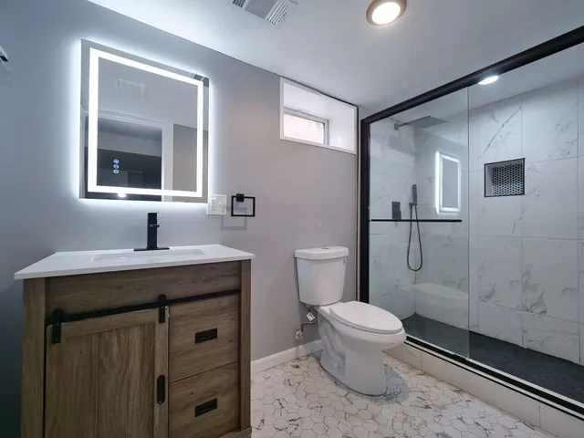 a bathroom with a granite countertop toilet sink and mirror