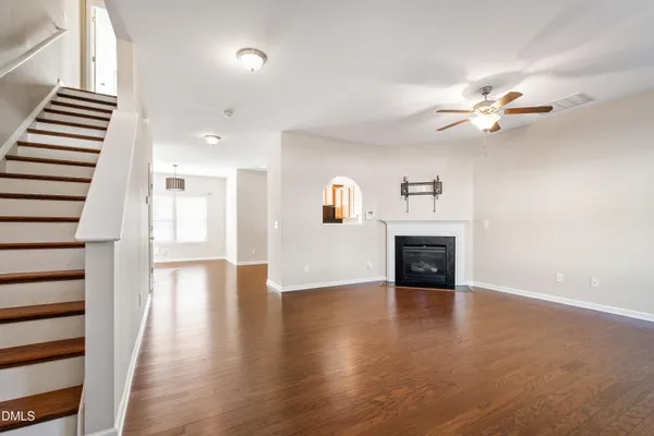 a view of a livingroom with fireplace wooden floor and a ceiling fan
