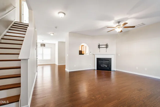 a view of a livingroom with fireplace wooden floor and a ceiling fan