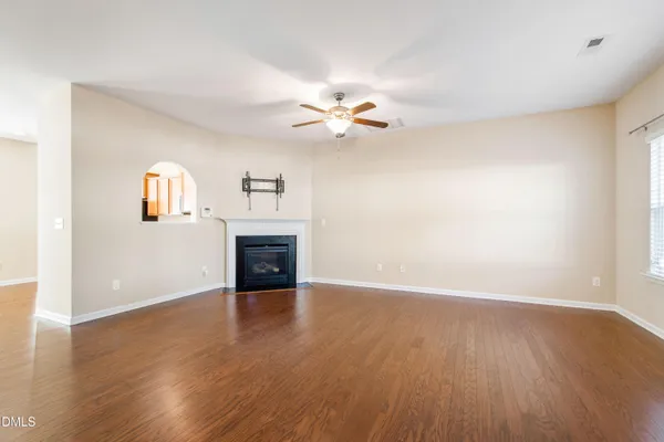 an empty room with a fireplace and wooden floor