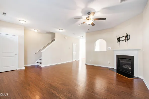 a view of an empty room with wooden floor fireplace and a window