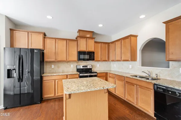a kitchen with granite countertop a refrigerator stove top oven and sink