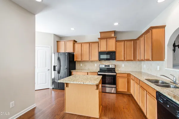 a kitchen with stainless steel appliances granite countertop a refrigerator stove top oven and sink
