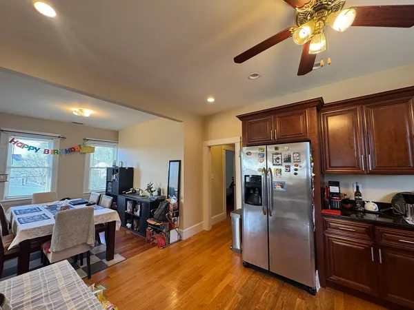 a kitchen with stainless steel appliances granite countertop a refrigerator dining table and chairs with wooden floor