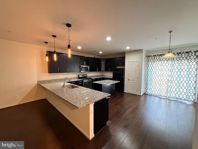 a kitchen with stainless steel appliances granite countertop a sink a stove and a wooden floor