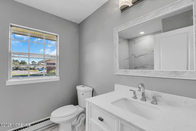 a bathroom with a toilet a sink a window and mirror