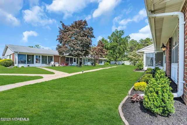 a view of a house with a big yard plants and large trees