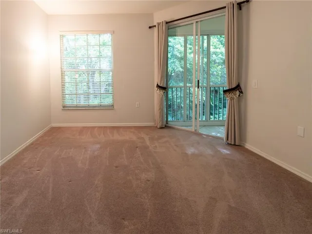 an empty room with large windows and wooden floor