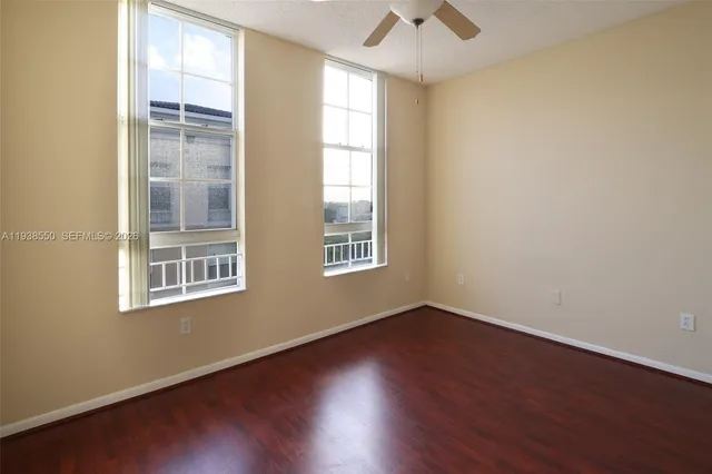 an empty room with wooden floor and fan