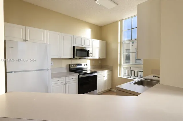 a kitchen with stainless steel appliances granite countertop a sink and a refrigerator